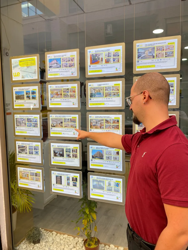Víctor Dabat Aracil señalando una de las propiedades en venta en el escaparate de Wereal